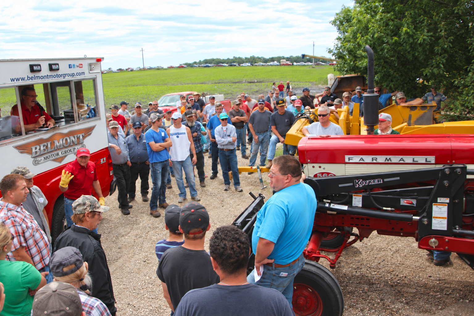 Auctioneer and visitors beside farm equipment